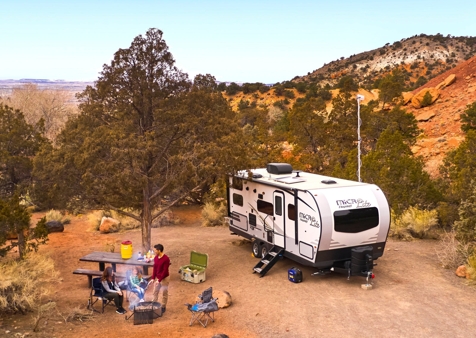Travel trailer parked at a remote desert campsite with a weBoost Destination RV antenna raised on a telescoping pole